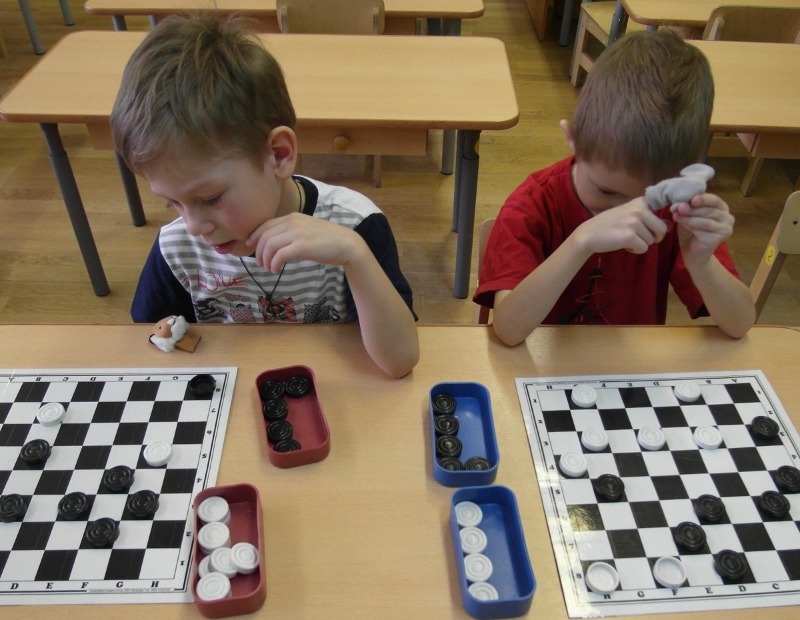 мальчики учатся играть в шашки